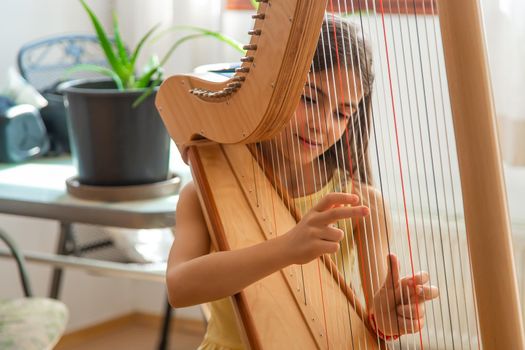 The child plays the harp. Selective focus. Kid.