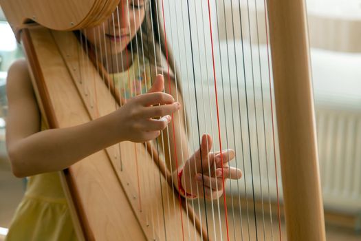 The child plays the harp. Selective focus. Kid.