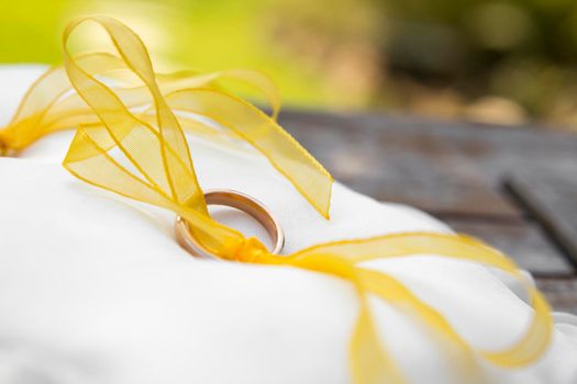 Wedding rings resting on a white pillow.