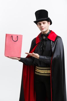 Vampire Halloween Concept - Happy handsome caucasian Vampire holding colorful shopping bag on white background