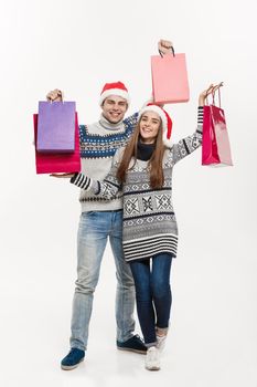 Christmas Concept - Full length Young attractive couple holding shopping bags isolated on white grey background