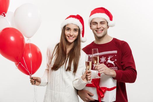 Christmas Concept - Young girlfriend holding balloon and champagne playing and celebrating with her boyfriend on Christmas day.