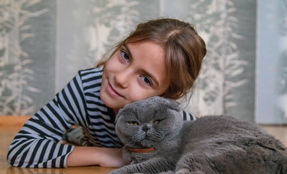 Child girl at home with a cat. Selective focus. Kid.