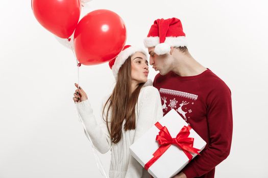 Christmas Concept - Young girlfriend holding balloon is hugging and playing with her boyfriend doing a surprise on Christmas.