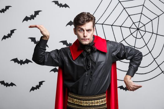 Vampire Halloween Concept - Portrait of handsome caucasian in Vampire halloween costume poining on side