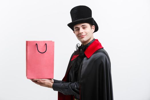 Vampire Halloween Concept - Happy handsome caucasian Vampire holding colorful shopping bag on white background