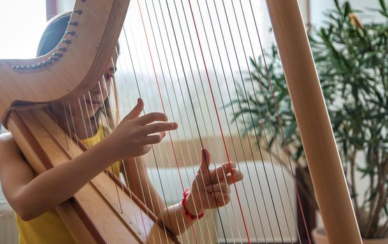 The child plays the harp. Selective focus. Kid.