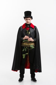 Vampire Halloween Concept - Full length Portrait of handsome caucasian Vampire giving red rose