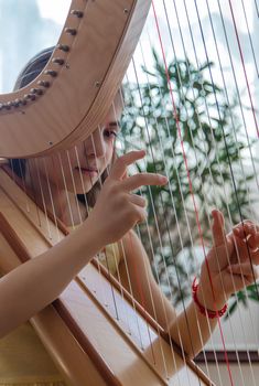 The child plays the harp. Selective focus. Kid.