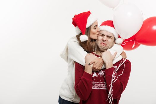 Christmas Concept - Young girlfriend holding balloon is hugging and playing with her boyfriend doing a surprise on Christmas.