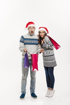 Christmas Concept - Full length Young attractive couple holding shopping bags isolated on white grey background