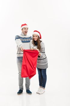 Christmas Concept - Full length Young attractive couple holding santa bag isolated on white grey background