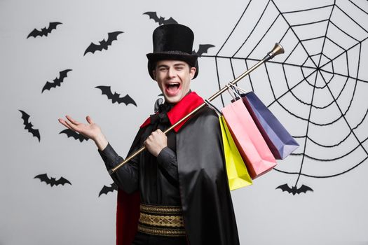 Vampire Halloween Concept - Happy handsome caucasian Vampire holding colorful shopping bag