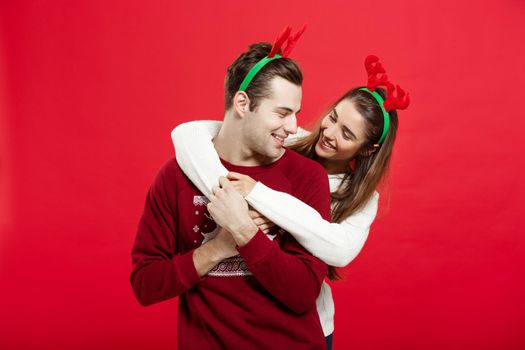 Christmas Concept - Romantic couple in a christmas sweaters huging each other.