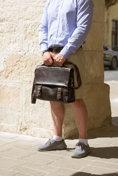 Man with a brown leather briefcase with antique and retro look. Outdoors photo.