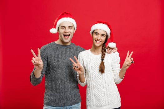 Christmas Concept - portrait lovely young couple showing two finger gesture with finger to camera.