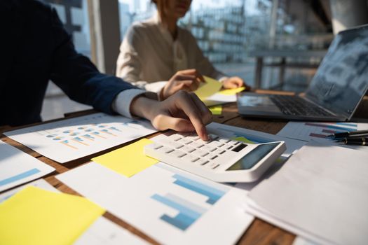 Close up Businessman and partner using calculator and laptop for calaulating finance, tax, accounting, statistics and analytic research concept.