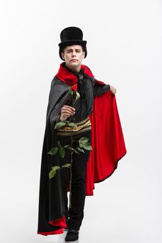 Vampire Halloween Concept - Full length Portrait of handsome caucasian Vampire giving red rose