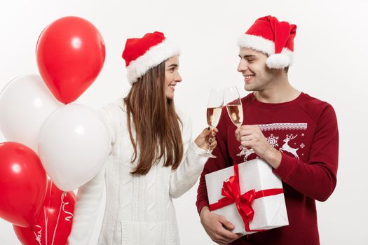 Christmas Concept - Young girlfriend holding balloon and champagne playing and celebrating with her boyfriend on Christmas day.