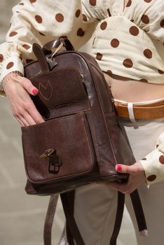 Woman with a brown leather backpack with antique and retro look. Outdoors photo.