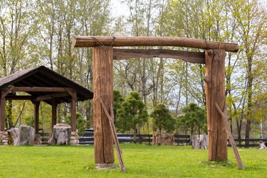 A wooden arch and a wooden gazebo standing on the territory next to the estate.