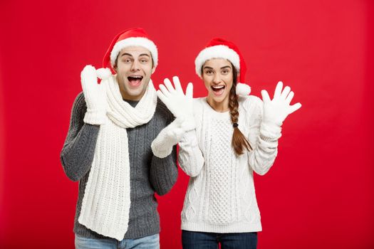 Portrait of a happy young couple posing over red studio background.