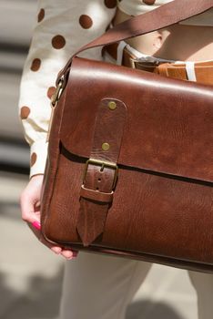 Woman with a brown leather briefcase with antique and retro look. Outdoors photo.