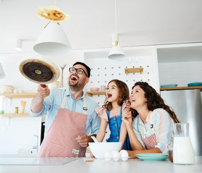 Family preparing pancakes in the kitchen at home