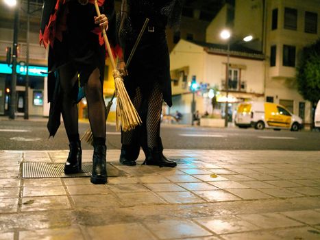 Cropped view of the legs of two young women dressed as witches for Halloween on the streets of Valencia, Spain.