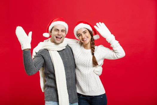 Portrait of a happy young couple posing over red studio background.