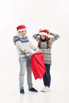 Christmas Concept - Full length Young attractive couple holding santa bag isolated on white grey background