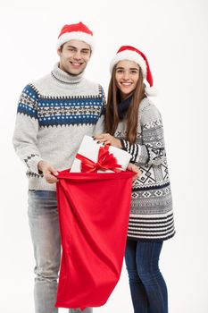 Chirstmas concept - young attractive couple with Santa red bag celebrating Chirstmas day. Isolated on White background.
