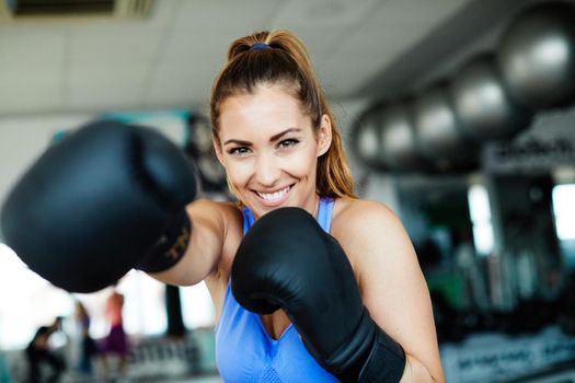 Portrait of healthy fit woman at the gym exercising boxing