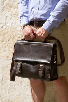 Man with a brown leather briefcase with antique and retro look. Outdoors photo.