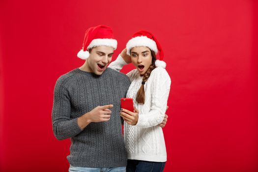 Christmas Concept - Young handsome and beautiful couple enjoy checking on mobile phone in christmas day.