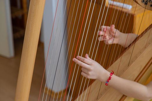 The child plays the harp. Selective focus. Kid.