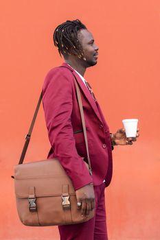 profile photo of an elegant black businessman in a suit with briefcase holding a coffee in his hand in front of a red background, copy space for text