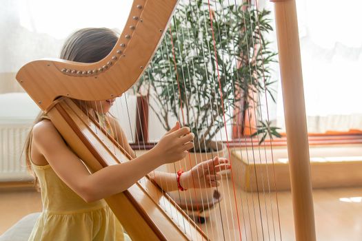 The child plays the harp. Selective focus. Kid.