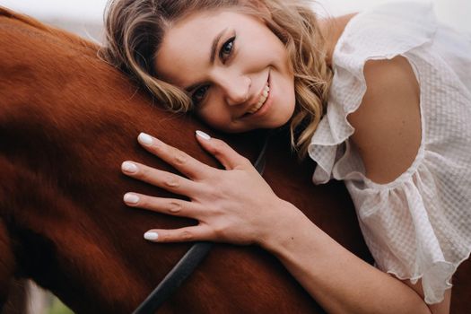 A woman in a white sundress riding a horse near a farm.