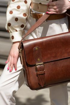 Woman with a brown leather briefcase with antique and retro look. Outdoors photo.