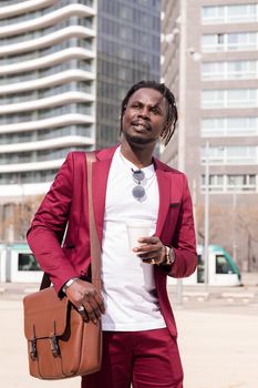 vertical photo of an elegant black businessman walking through the city's financial downtown with a coffee and briefcase, copy space for text