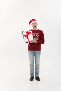 Christmas Concept - Full-length handsome young man in sweater with white christmas gift.