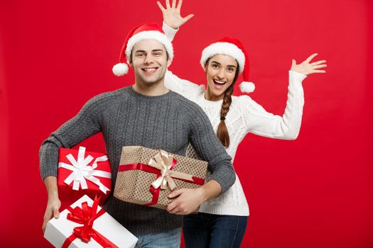 Christmas Concept - Young attractive couple holding a lot of presents enjoy shopping and celebrating in Christmas day.