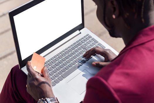 unrecognizable man paying with his credit card for the online purchase made with his laptop computer, concept of technology and online shopping