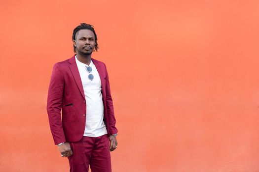 african businessman in suit with afro posing looking at camera in front of a red background, copy space for text