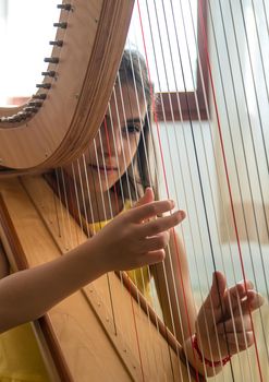 The child plays the harp. Selective focus. Kid.