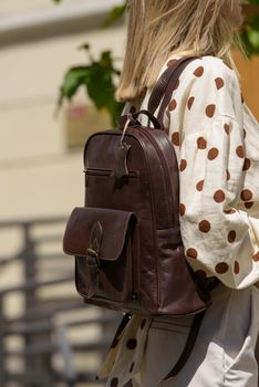 Woman with a brown leather backpack with antique and retro look. Outdoors photo.