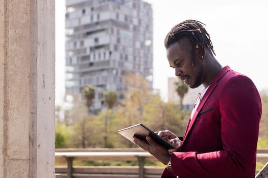black businessman using a tablet outdoors in the city, technology and remote work concept, copy space for text
