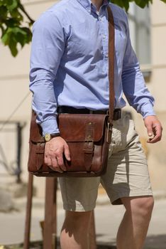 Man with a brown leather briefcase with antique and retro look. Outdoors photo.