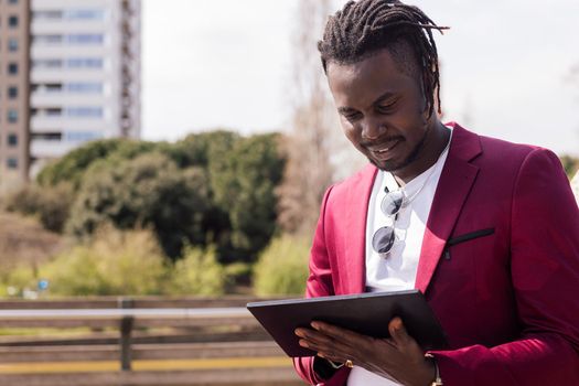 african businessman using a tablet outdoors in the city, technology and remote work concept, copy space for text